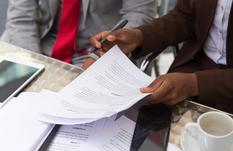 Businessman consulting legal expert in coffee shop. Closeup of business man and woman sitting in cafe and reading documents. Paperwork concept
